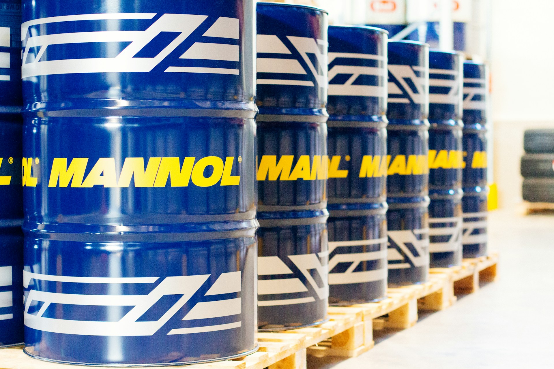 Rows of industrial steel drums on wooden pallets staged in a clean distribution warehouse